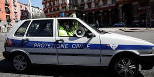 Ein Polizeifahrzeug mit Lautsprecher im Fenster fährt durch eine Starße in Neapel.