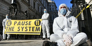 Demonstranten in Schutzanzügen fordern härtere Maßnahmen gegen den Coronavirus in Großbritannien.