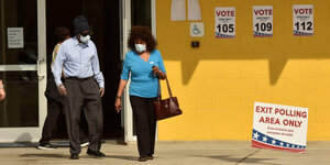 Ein Mann und eine Frau mit Gesichtsmasken verlassen ein Wahllokal in Florida