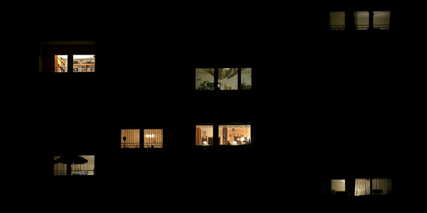 Licht dringt durch die Fenster von Wohnungen eines Wohnblocks.