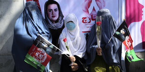 Verschleierte Frauen am Internationalen Frauentag mit Blumen in Kabul.