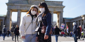 Touristen aus Hongkong stehen mit Mundschutz vor dem Brandenburger Tor
