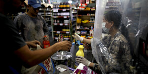Ein Frau mit Mundschutz steht in einem Supermarkt hinte reiner Plastikfolie.