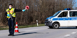 ein Ordnungshüter, im Hintergrund ein Auto und ein Straßenschild