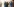 Ein Mann steht mit erhobenen Händen vor Polizisten in Schutzanzügen.