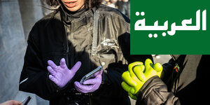 امرأة ترتدي قفازات مطاطية أرجوانية. علم أخضر بكلمة العربي