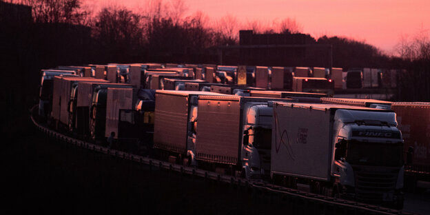 LKWs stauen sich auf einer Autobahn im Sonnenuntergang.