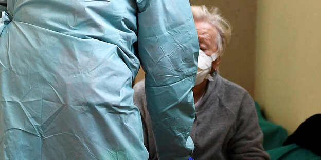 Medizinisches Personal hilft älterem Patient mit Atemschutz Medizinisches Personal hilft älterem Patient mit Atemschutz