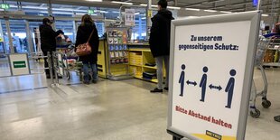 Ein Schuld in einem Berliner Großmarkt biettet die Kunden, in Corona-Zeiten genug Abstand beim Anstehen zu halten