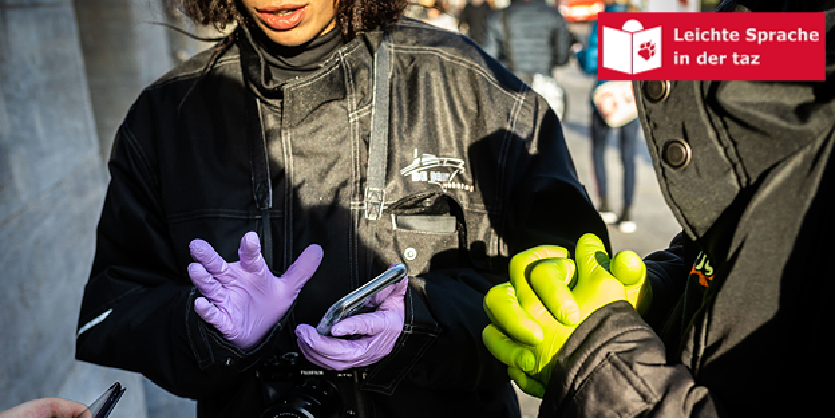 Zwei Personen tragen Einweghandschuhe, eine hält ein Smartphone