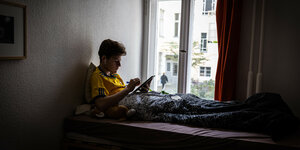 Ein Junge lernt im Bett mit IPad