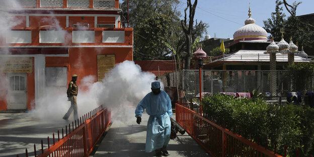 Ein Mann lauft durch einen Nebel einer Desinfektionsmassnahme.