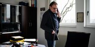 Der Bürgermeister von Grünheide, Arne Christiani, steht in seinem Büro und telefoniert