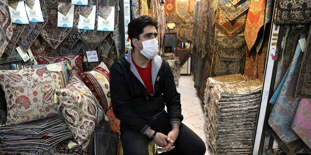 Mann mit Atemschutzmaske vor der Auslage eines Stoffladens