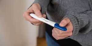 eine Frau hält einen schwangerschaftstest in der hand