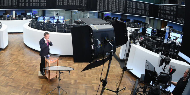 Ein Fernsehreporter steht im Handelsraum der Frankfurter Börse.