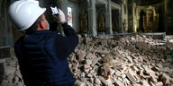 Ein Bauarbeiter fotografiert Trümmer einer Kirche