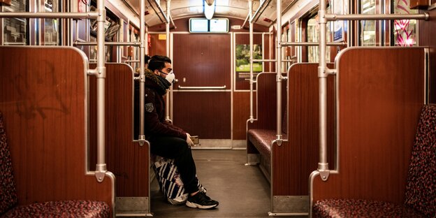 Ein Mensch sitzt in einem leeren U-Bahn Abteil.