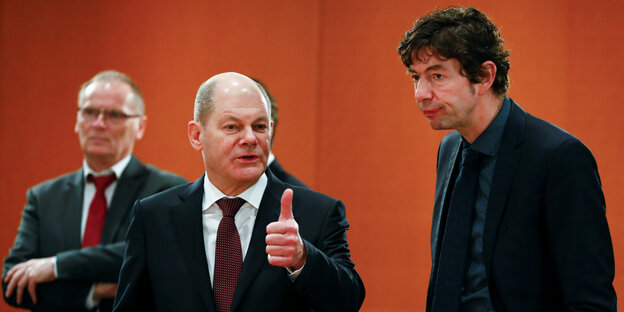 Finanzminister Scholz mit erhobenem Daumen neben dem Virologen Drosten
