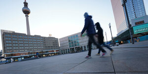 Zwei Menschen laufen über den Alexanderplatz