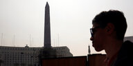 Silhouette eines jungen Mannes vor einem Obelisken