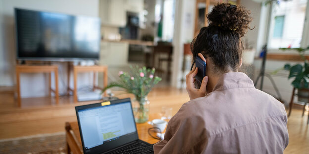 Eine Frau nimmt aufgrund der Ausbreitung des Coronaviruses aus ihrem Wohnzimmer an einer Telefonkonferenz teil