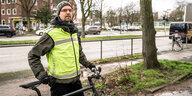 Ein Mann mit Schutzweste steht mit seinem Fahrrad auf einem Radweg