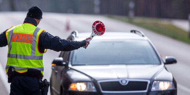 Ein Polizist winkt ein Auto an den Straßenrand