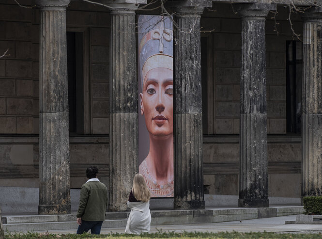 Menschen laufen vor einem Plakat mit Nofrete vorbei