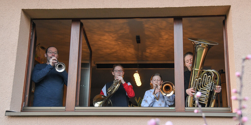 Eine Familie musiziert am zur Straße geöffneten Fenster