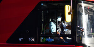Busfahrer mit Maske in einem roten Bus