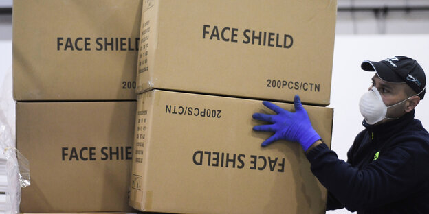 Ein Mann mit Schutzkleidung hebt Kisten von einer Palette