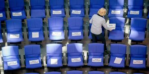 Blaue Sitze im Plenarsaal werden markiert mit Zetteln zum Abstandhalten