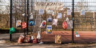 An einem Zaun hängen gefüllte Tüten