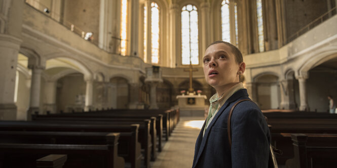 Eine Frau mit rasiertem Kopf in einer Kirche.