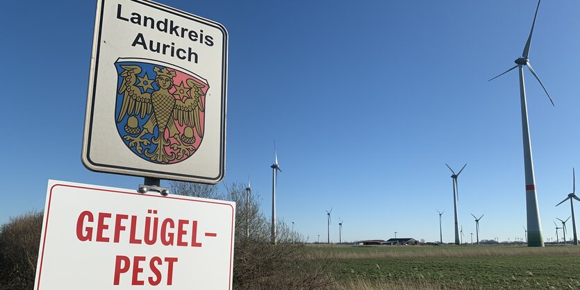 Auf einem Schild unter dem Wappen des Landkreis Aurich steht „Geflügelpest Sperrbezirk“.