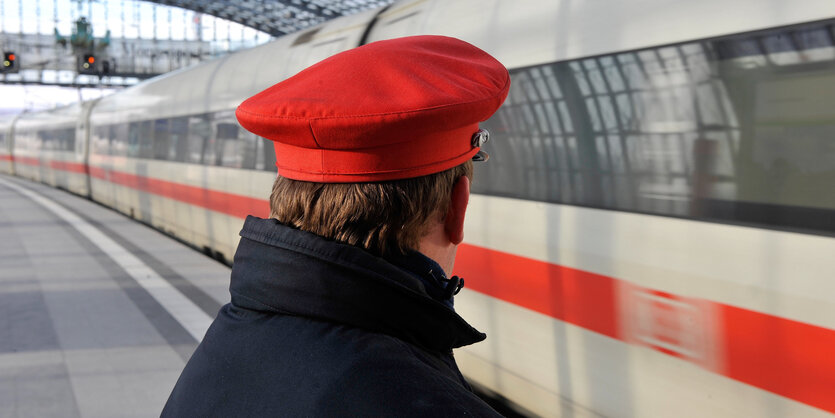 Ein bahn-Mitarbeiter steht im Berliner Hauptbahnhof am bahnsteig an einem einfahrenden ICE.