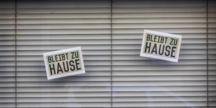 In einem Laden hänger Schilder mit "Bleibt zu Hause" Aufschrift.