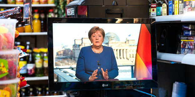 ein TV-Geät steht in einem Kiosk, auf dem die Rede von Angela Merkel übertragen wird