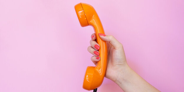 Frauenhand mit orangfarbenem Telefonhörer vor rosa Wand