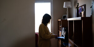 Frau steht an einem Laptop im Wohnzimmer
