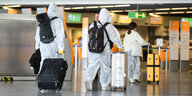 Chinesische Touristen sind in Schutzanzügen, mit Atemmasken und Handschuhen im Terminal