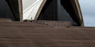 Die leeren großen Treppenstrufen der Oper in Sydney. Nur ganz oben steht ein Mann in Warnweste.