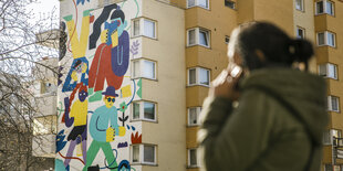 Eine Frau steht vor der einer bunte bealten hausfassade