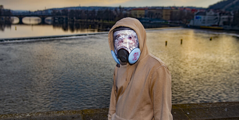 Ein junger Mann mit buntem Mundschutz auf einer Brücke