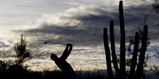 Ein Golfer blickt seinem Ball hinterher