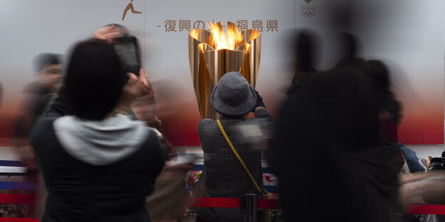 In Fukushima fotografieren Menschen das olympische Feuer