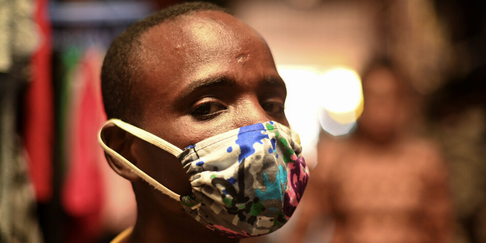 Ein Mann aus Ruanda trägt einen bunten Mundschutz