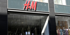 Geschlossene Glastüren und ein Schaufenster mit Schaufensterpuppen, darüber der Schriftzzug H&M