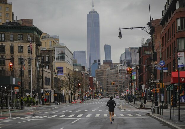 Ein einsamer Jogger auf der 7th Avenue in New York, USA. Die Straßen sind leer. Am Ende der Straße sieht man Hochhäuser.